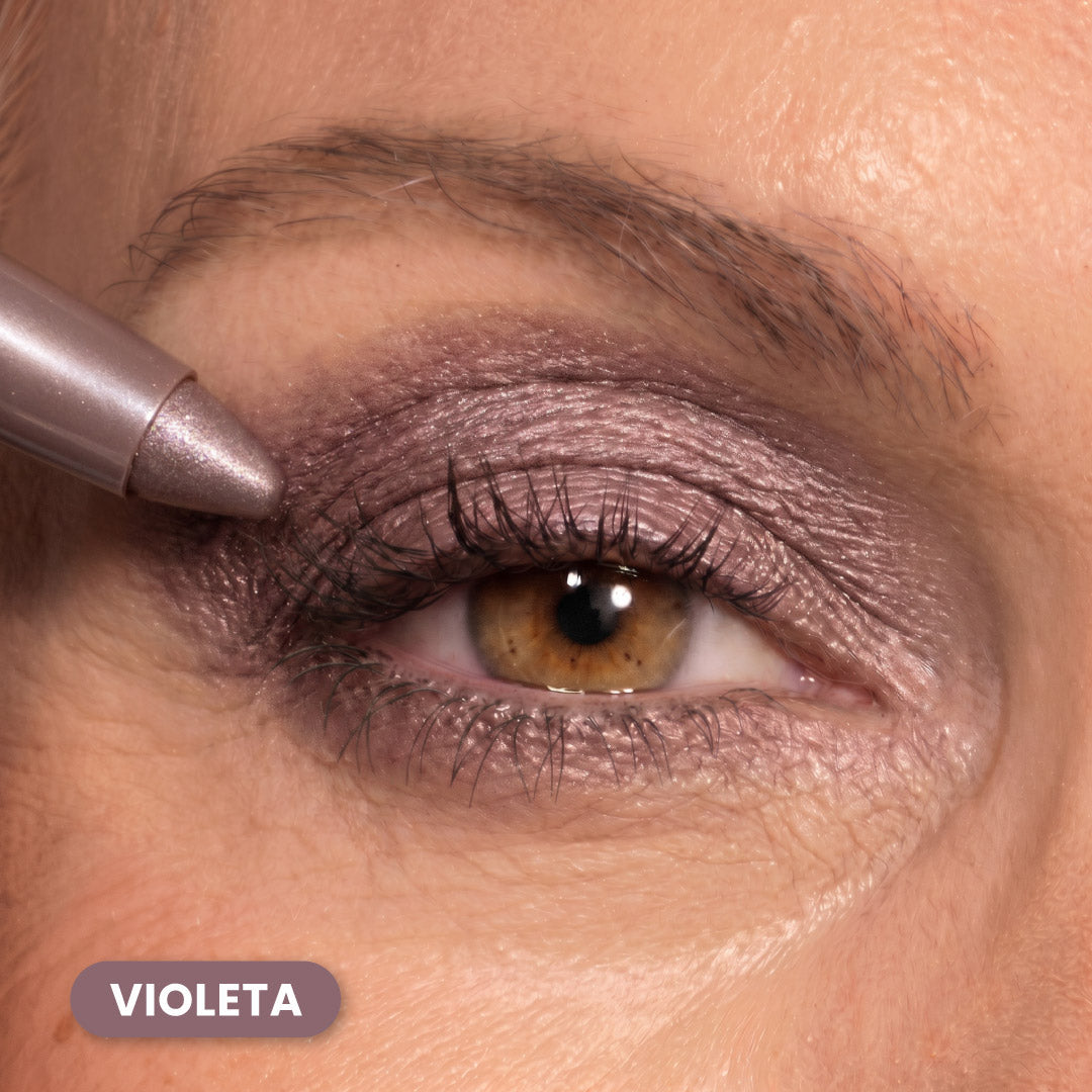 Close-up of a persons eye with shimmery violet eyeshadow and pencil being applied to the eyelid. The word Violeta is displayed in a purple box at the bottom left.