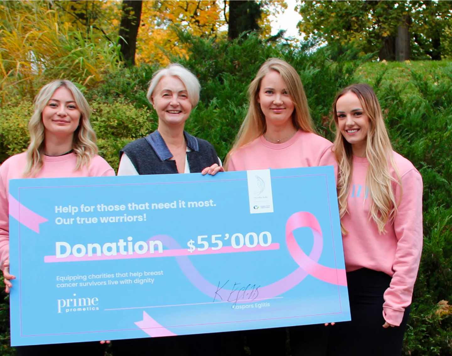 Prime Prometics team presenting a $55,000 donation check for breast cancer support.