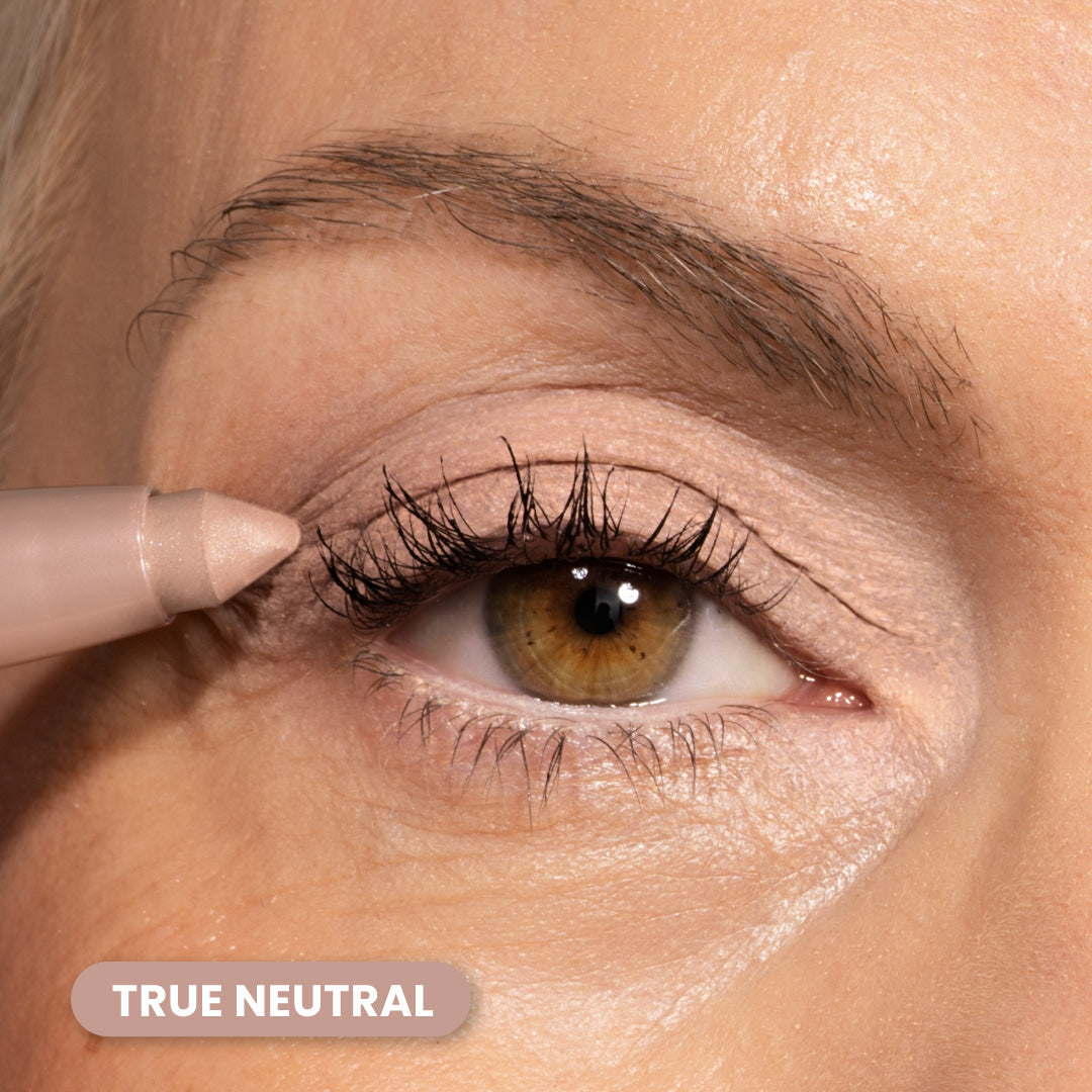 A close-up of a persons eye with brown iris, using a neutral-toned makeup pencil on the eyelid. The label TRUE NEUTRAL appears in the bottom left corner.